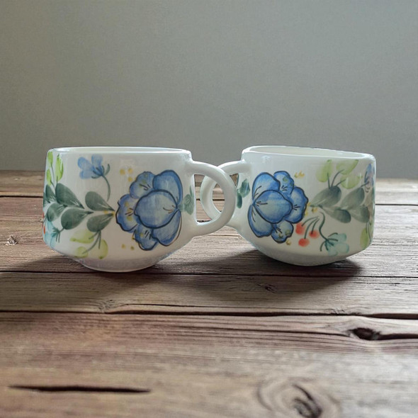 An elegantly displayed pair of ceramic tea cups, highlighting their artistic floral patterns and comfortable, compact design.