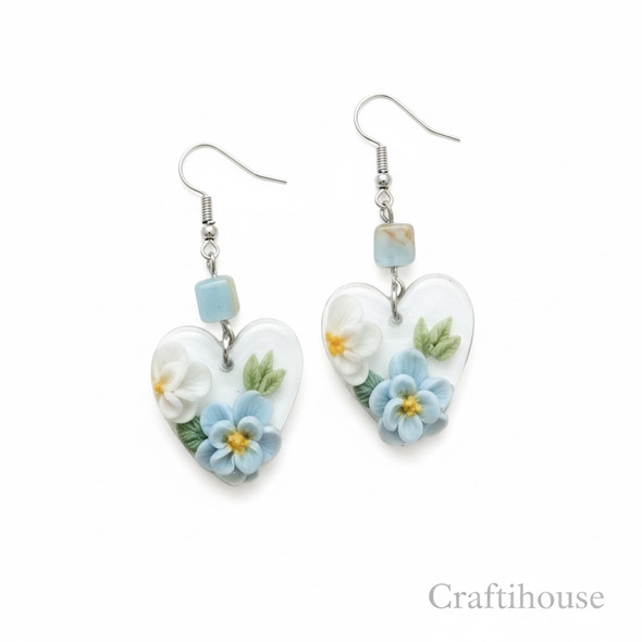 A pair of handcrafted transparent heart earrings featuring 3D sculpted sky blue and white flowers with green leaves.