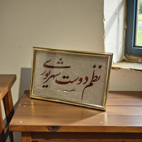 A framed Persian calligraphy piece featuring terracotta and burgundy script with gold accents on textured paper, presented in a polished gold-toned frame.