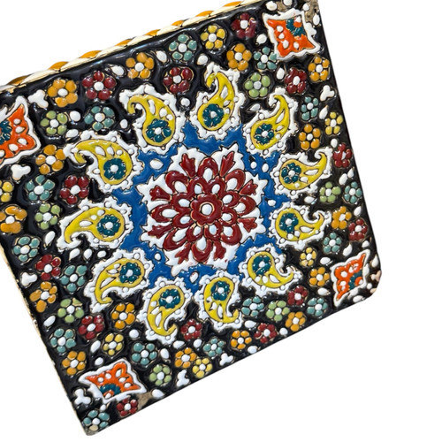 Close-up of a blue and orange embossed floral mandala pattern on a hand-painted glazed clay tile.