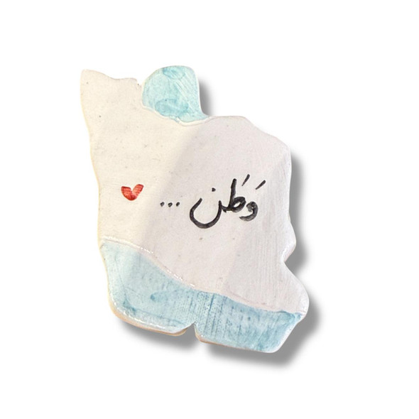A ceramic fridge magnet in the shape of the Iran map with "Vatan" written in Persian calligraphy on a white background.