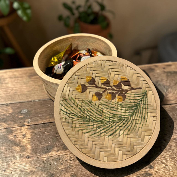 A 16 cm round storage box made from wooden palm leaf featuring a colorful hand-painted lid with floral and bird motifs.