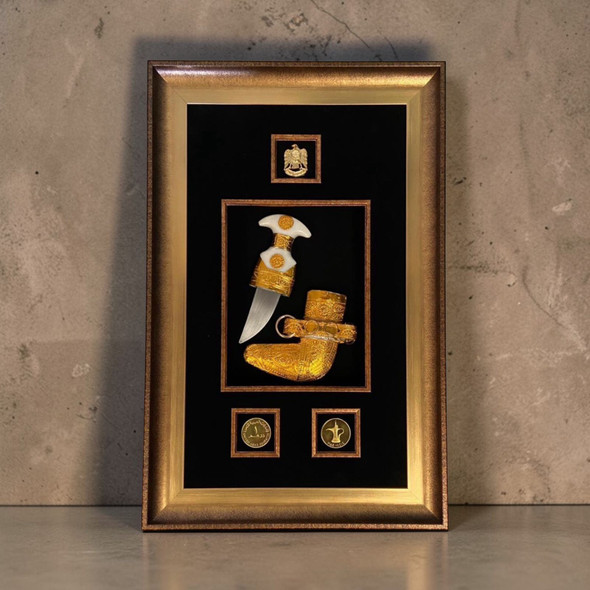 A luxury framed display of a golden traditional UAE dagger (Khanjar) set against a rich fabric background.
