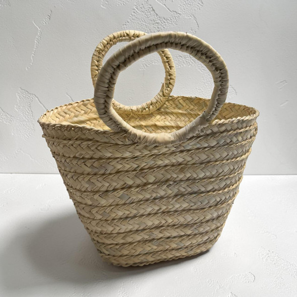 A large hand-woven natural palm leaf storage basket with two sturdy braided handles