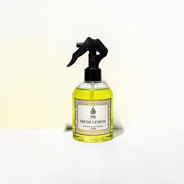 The 275ml luxury Fresh Lemon home fragrance spray positioned next to delicate room textiles, focusing on its high-end architectural bottle design