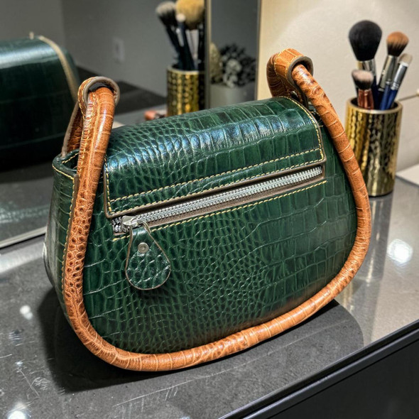 Side and back profile photo of the green embossed cow leather shoulder bag, showcasing the substantial depth, integrated rear metallic zipper pocket with a leather pull tab, and integrated loops for the carrying strap on a dark reflective surface.