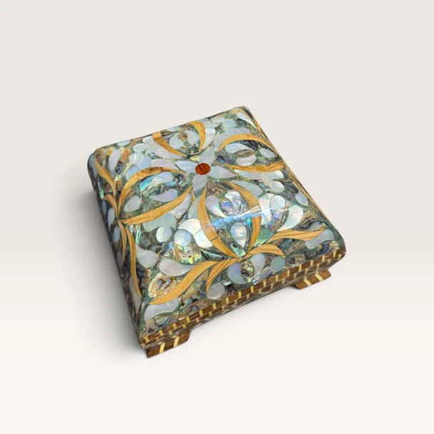 A detailed close-up highlighting the iridescent mother-of-pearl and natural shell inlays, fine wooden micro-mosaic work, and floral motifs on the lid of the artisan box.