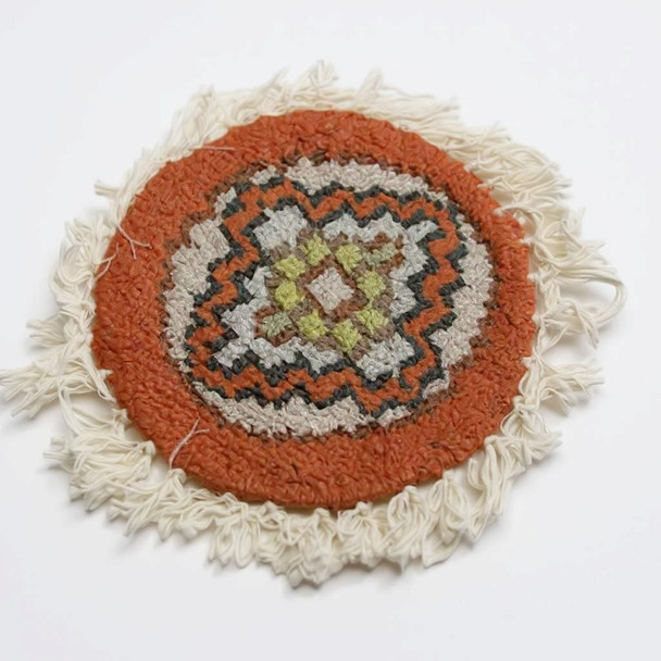 The round carpet coaster featured on a minimalist surface, emphasizing its unique heritage-inspired geometric aesthetic.