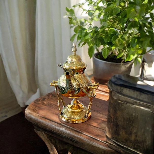 A professionally presented traditional brass teapot with an integrated warmer stand and burner set against a clean white background.