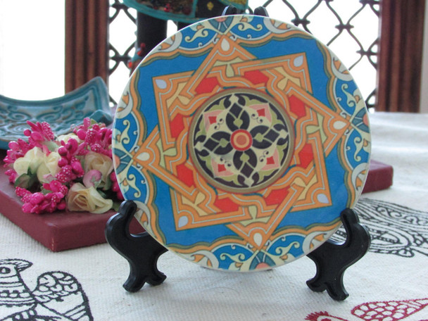 A premium ceramic coaster featuring a vibrant and intricate traditional Arabesque star pattern in blue, orange, and red.
