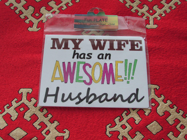 A vibrant 11x9 cm rectangular aluminium fridge magnet featuring bold, colorful typography with the humorous quote 'My Wife has an AWESOME!!! Husband'.