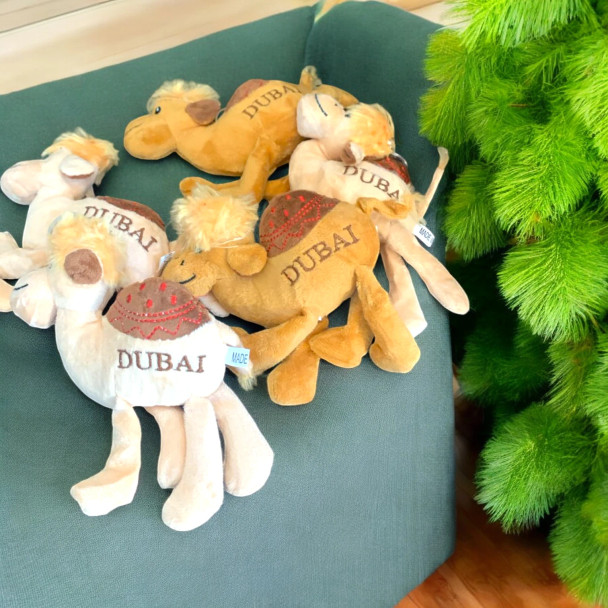 A soft, cuddly plush camel souvenir toy featuring "Dubai" embroidered on its side, perfect for gifting or as a travel keepsake.