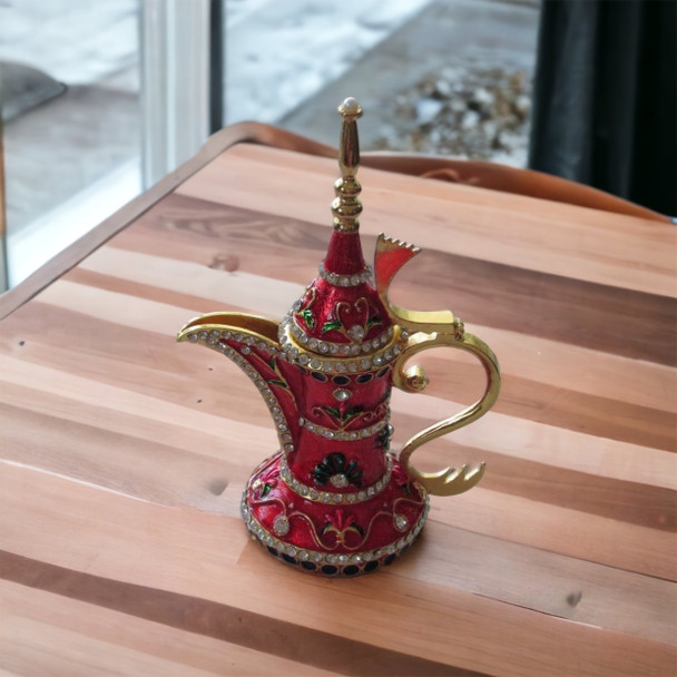 Close-up of the delicate white and green floral patterns hand-painted on the vibrant red surface of the 20 cm brass Dallah.