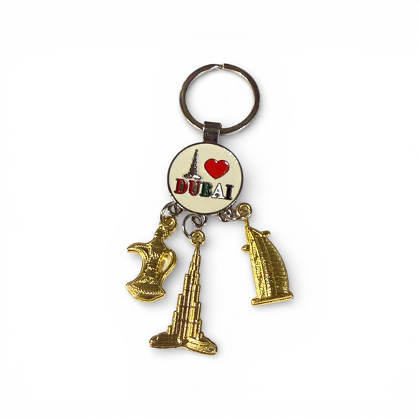 A gold-tone keychain featuring an "I Love Dubai" heart emblem and three hanging charms representing Dubai's iconic landmarks.