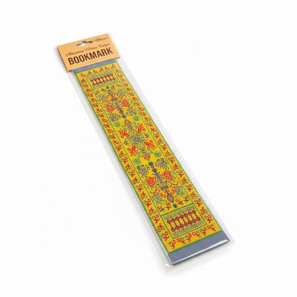 A luxury carpet style woven bookmark sitting elegantly inside a large leather-bound book as a cultural library accessory.