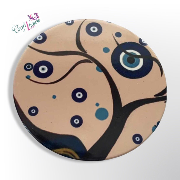 A round ceramic tea coaster with a detailed printed artistic design