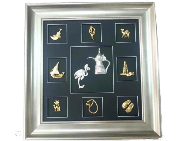 A 40x55 cm framed UAE souvenir featuring a striking arrangement of golden regional miniatures and a central silver coffee pot and falcon motif against a black background.