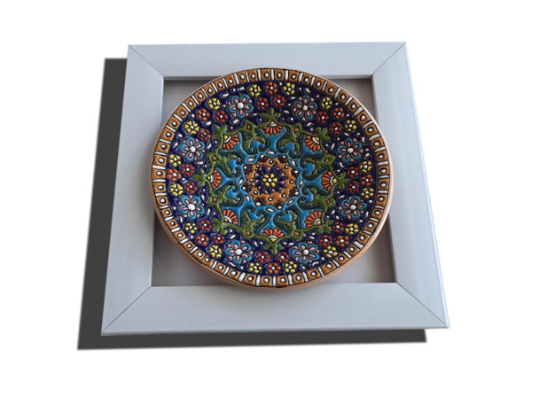 A 16 cm embossed enamel-painted clay plate featuring intricate assorted patterns, mounted inside a clean white wall frame.