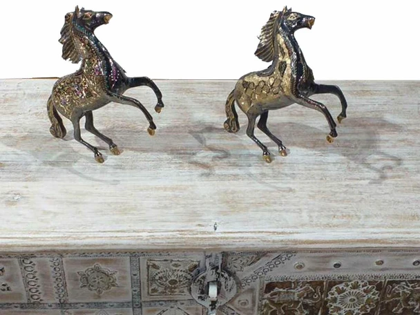 Detailed close-up of two elegant metal horse sculptures featuring intricate engravings and a classic standing pose.