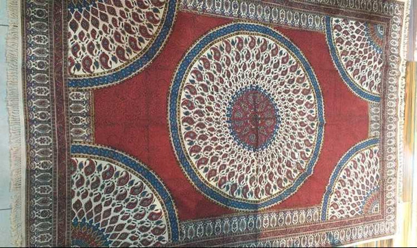 A professionally arranged 200x135 cm block printed tablecloth featuring a traditional circular medallion pattern in deep red and blue tones displayed on a flat surface