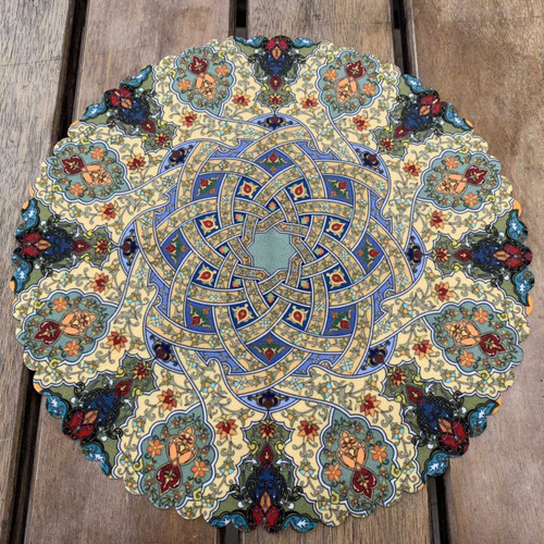 A 28 cm round velvet placemat on a wooden surface featuring a traditional interlaced star pattern and dense floral borders.