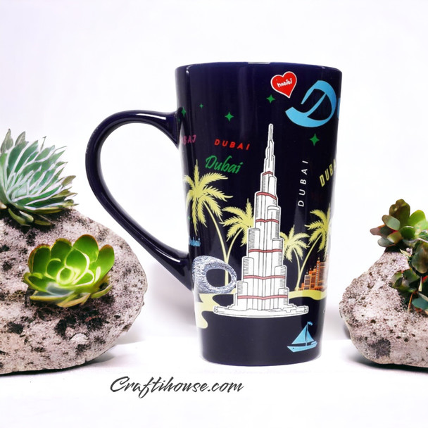 A professional product shot of the tall black Dubai ceramic mug styled neatly on a clean white surface with decorative stones.