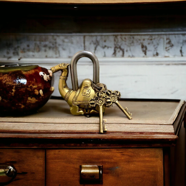 A handcrafted solid brass camel lock with traditional saddle engravings and two brass skeleton keys.