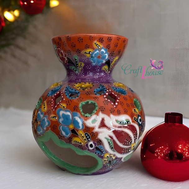 Intricately designed ceramic oil burner with ornate cutouts and colorful artistic patterns.