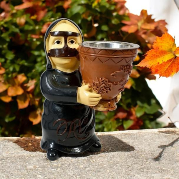 A traditional Omani woman figurine incense burner wearing a black abaya and holding a decorated mabkhara bowl outdoors.