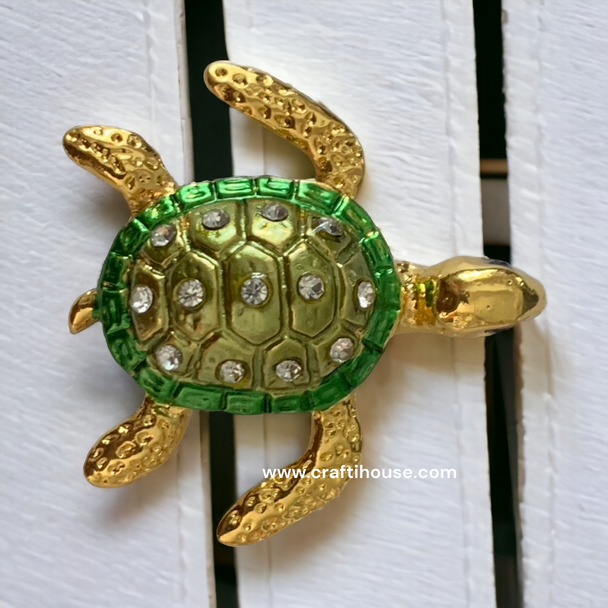 A stylish display of the 4x4 cm jeweled turtle fridge magnet resting on a white slatted surface.