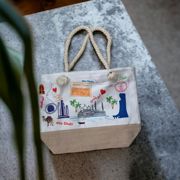 A professional product presentation of the Abu Dhabi landmarks canvas tote bag against an indoor background.