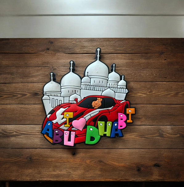 Close-up of a detailed PVC souvenir magnet featuring Abu Dhabi landmarks and a sports car.