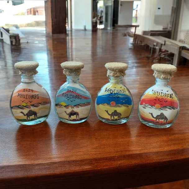 A 13 cm Abu Dhabi sand bottle featuring a handmade assorted pattern desert scene with natural sand colors.