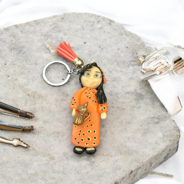 Lifestyle presentation of the premium handmade polymer clay traditional doll charm clipped onto a luxury handbag, making for a lovely gift token or a unique souvenir from Dubai.