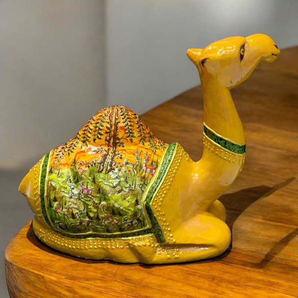Close-up view of the detailed hand-painted landscape and patterns on the blanket of a papier-mache camel statue.