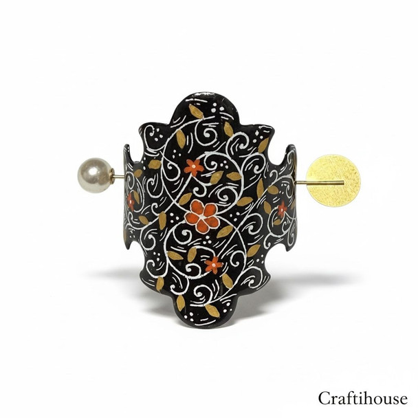 Artisan at work painting a copper Minakari hair clip, demonstrating the fine brushwork of traditional enameling