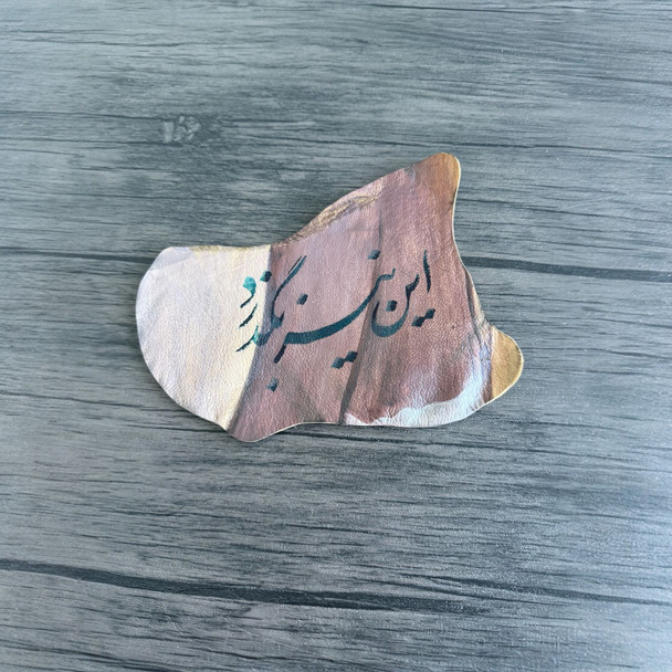 Persian calligraphy on natural leather featuring the phrase “In Niz Bogzarad