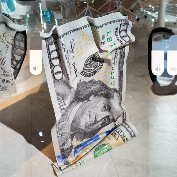 A vertical, self-standing 3D dollar bill sculpture made of crumpled aluminium, shown in a modern luxury living room