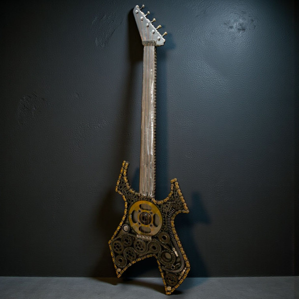 A 125 cm tall industrial sculpture of a guitar made from upcycled gears, chains, and scrap metal against a dark wall.