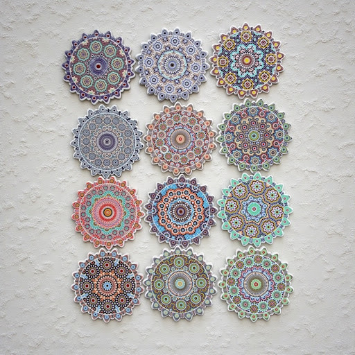 A grid of twelve different ceramic coasters showing a variety of vibrant mandala and geometric patterns.