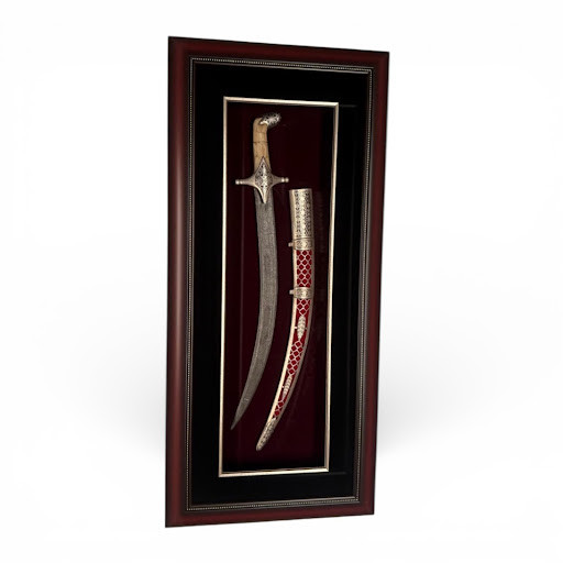 A luxury vertical framed display of a curved Persian Shamshir sword and red scabbard on black velvet with a dark wood-grain frame.