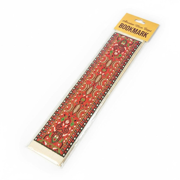 A red Kilim pattern miniature woven carpet bookmark with traditional tribal geometric designs in its retail packaging.