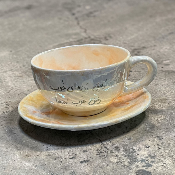 A Handmade White Ceramic Cup And Saucer Set With Black Calligraphy Celebrating Friendship.