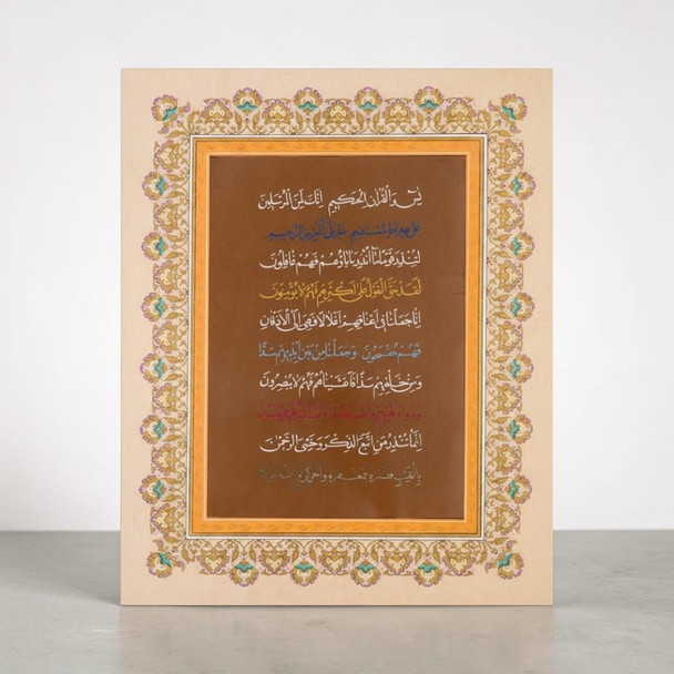 A 35.5×28.4 cm polychrome Islamic calligraphy manuscript of Surah Ya-Sin Verse 1 in multi-color Naskh script on cardboard.
