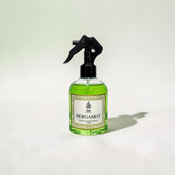 The 275ml luxury Bergamot home fragrance spray positioned next to delicate room textiles, focusing on its high-end architectural bottle design.