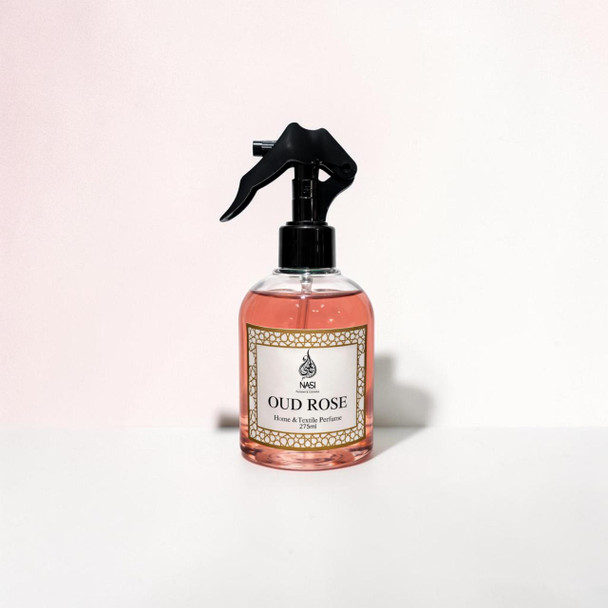 The 275ml luxury Oud Rose home fragrance spray positioned next to delicate room textiles, focusing on its high-end architectural bottle design.