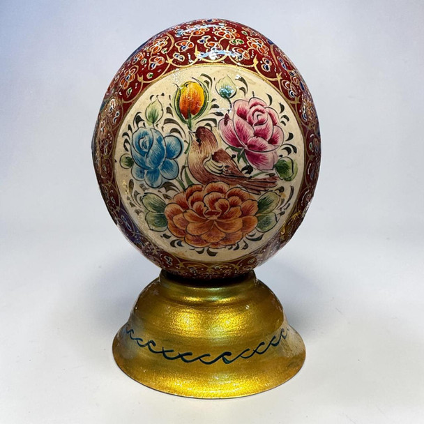 Artisan-crafted decorative ostrich egg on a vibrant golden display stand.
