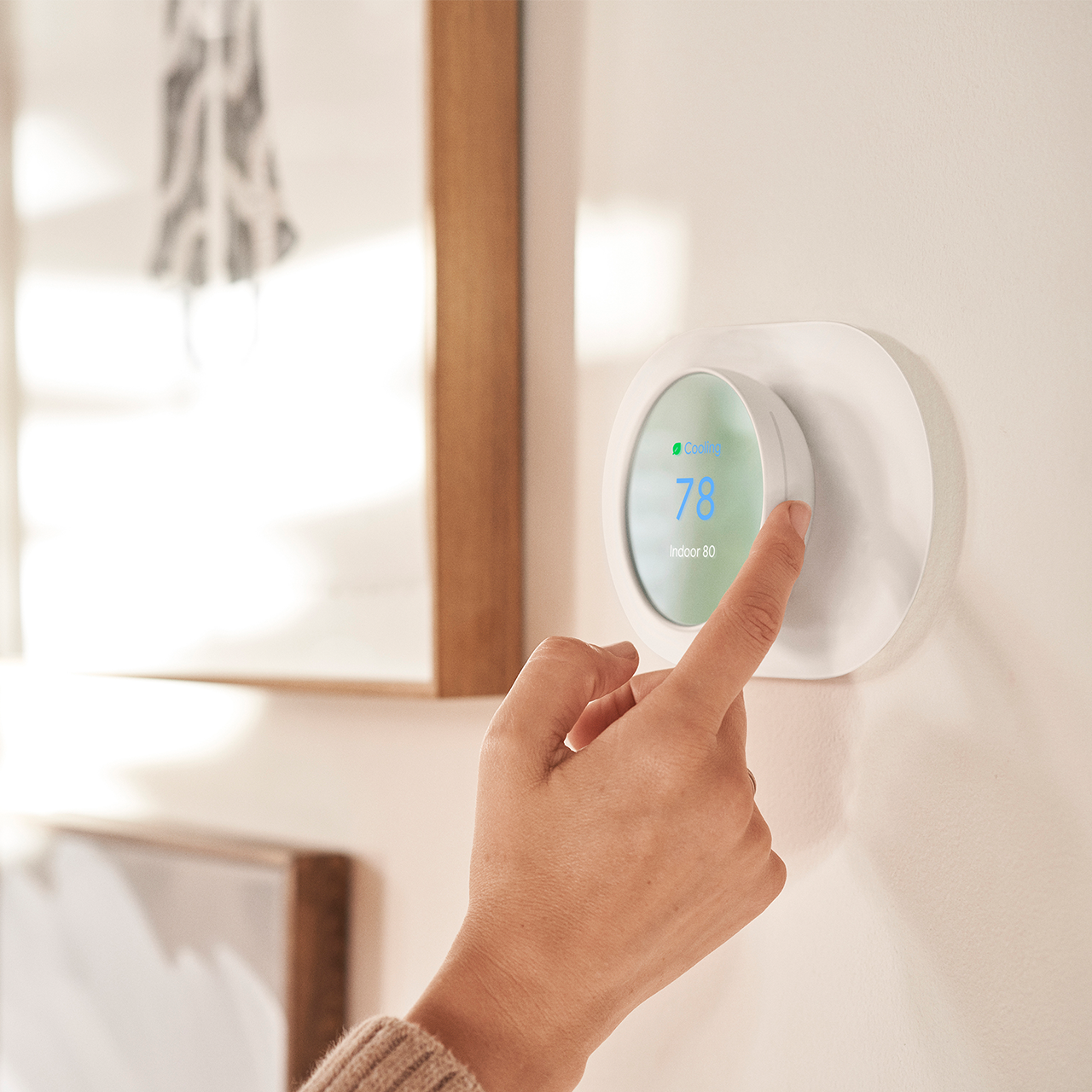 Person adjusting nest thermostat temperature on the wall