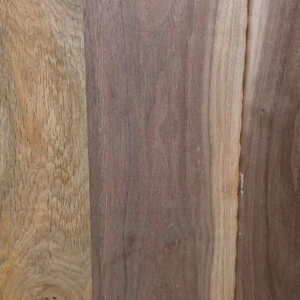Close-up of planed oak and walnut boards side by side, showing the open grain of the tan oak and the darker, fine-grained walnut