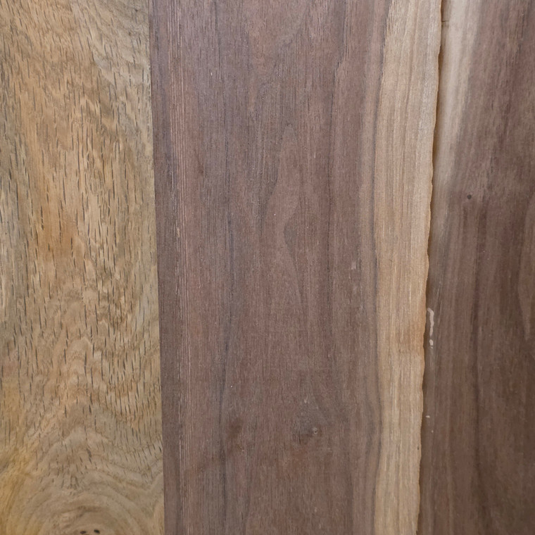 Close-up of roughsawn oak and walnut boards side by side, showing the open grain of the tan oak and the darker, fine-grained walnut
